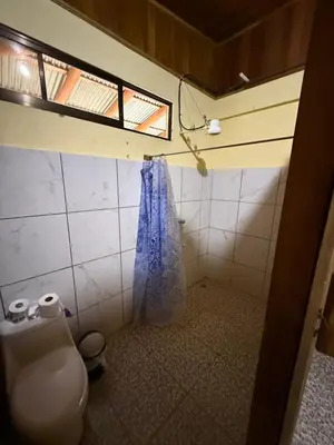 a bathroom with a toilet and a blue shower curtain at Casa Terracota in Bejuco