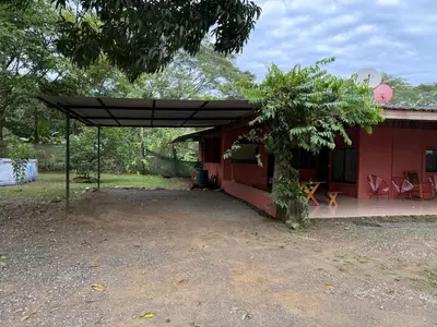 a red house with a black canopy next to a tree at Casa Terracota in Bejuco