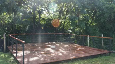 a wooden deck in a yard with trees in the background at Casa Andalucia Apartments in Santo Domingo