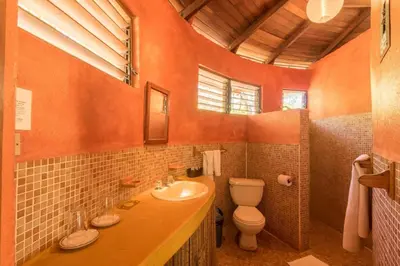 an orange bathroom with a toilet and a sink at Hotel Playa Negra in Playa Negra