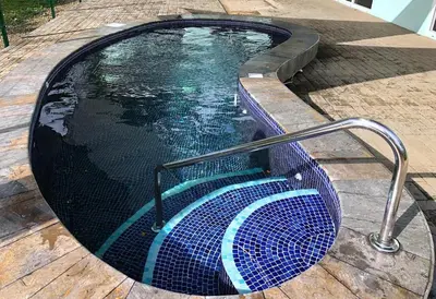 a swimming pool with a metal rail next to it at Screened-In Porch! Short Walk To Beach! in Sámara