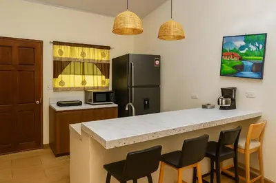 a kitchen with a counter with chairs and a refrigerator at Casa Sol in Santa Rita