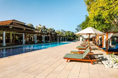 a row of lounge chairs and umbrellas next to a swimming pool at Luxury Condo at Reserva Conchal with Incredible Ocean Views and Exclusive Beach Club Access in Brasilito