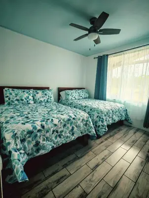 a bedroom with two beds and a ceiling fan at Cabaña Tranquila en la Naturaleza in Tigra