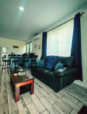 a living room with a black couch and a table at Cabaña Tranquila en la Naturaleza in Tigra