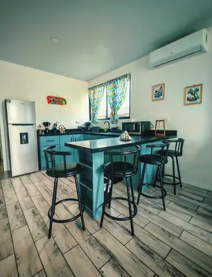 a kitchen with a counter and stools and a refrigerator at Cabaña Tranquila en la Naturaleza in Tigra