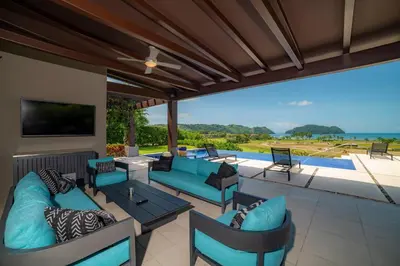 a patio with blue furniture and a view of the ocean at Casa Blue Sail 6 bdr Ocean View in Herradura