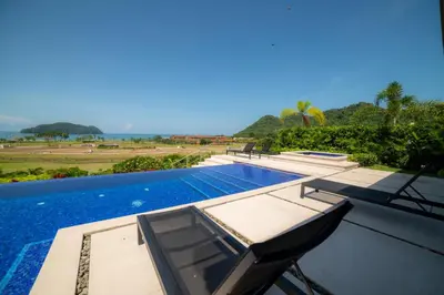 a swimming pool with two lounge chairs on a building at Casa Blue Sail 6 bdr Ocean View in Herradura