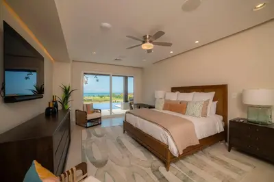 a bedroom with a bed with a ceiling fan and a television at Casa Blue Sail 6 bdr Ocean View in Herradura