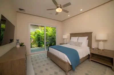 a bedroom with a bed with a ceiling fan and a window at Casa Blue Sail 6 bdr Ocean View in Herradura