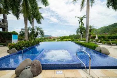 a swimming pool with palm trees in a resort at Vista Bahia 1G - 3bed 3 bath Ocean View in Herradura