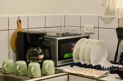 a kitchen counter with a microwave and plates on a counter at Comfort Near the Sea Valgreenplace Herradura in Herradura