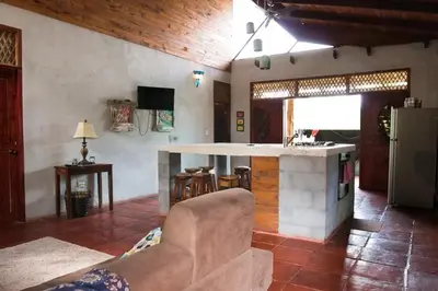 a living room with a kitchen with a counter top at Cabuya Lodge in Cabuya