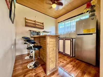 a kitchen with a refrigerator and a counter with stools at 2 Tiny Houses Private Pool Volcano View 6 people in Fortuna
