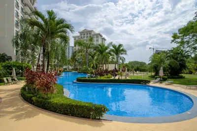 a large swimming pool with palm trees and a building at Jaco Bay 4303 in Jacó