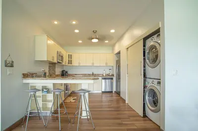 a kitchen with a washer and dryer and two bar stools at Jaco Bay 4303 in Jacó