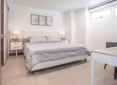 a white bedroom with a bed and a desk at Selva Coral 0701 in Jacó
