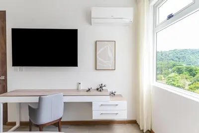 a white office with a desk and a tv on a wall at Selva Coral 0701 in Jacó