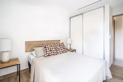 a white bedroom with a bed and a window at Torres del Mar 1202 in Jacó