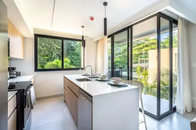 a kitchen with white countertops and large windows at Torres del Mar 1202 in Jacó