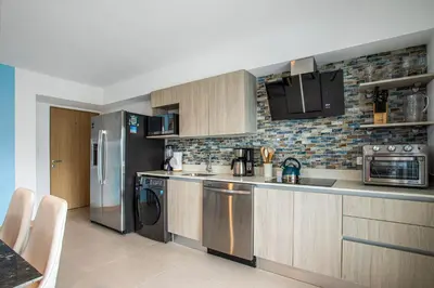 a kitchen with stainless steel appliances and wooden cabinets at Viva Jaco Viva Jaco (10-03B) in Jacó