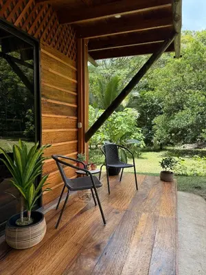 a porch of a house with two chairs and a table at Casa Oropéndola Refugio natural en Guanacaste in Bagaces