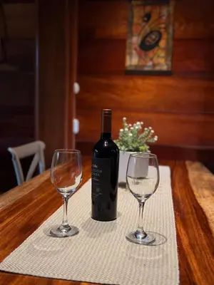a bottle of wine sitting on a table with two wine glasses at Casa Oropéndola Refugio natural en Guanacaste in Bagaces