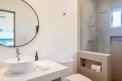 a white bathroom with a sink and a mirror at Casa Ocean with Studio -Triskele Retreat in Esterillos