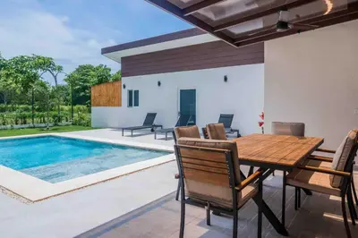 a dining room with a table and chairs next to a pool at Casa Ocean with Studio -Triskele Retreat in Esterillos