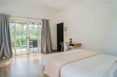 a bedroom with a bed and a table and a balcony at Casa Ocean with Studio -Triskele Retreat in Esterillos