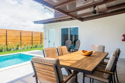 a dining room with a wooden table and chairs and a pool at Entire Property - Triskele Retreat in Esterillos