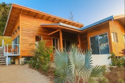 a wooden house with a lot of plants in front of it at luxury wooden house mountain view in Hojancha