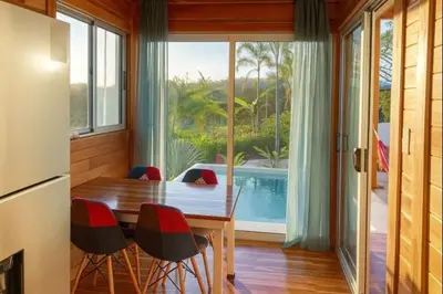 a dining room with a table and chairs and a pool at luxury wooden house mountain view in Hojancha