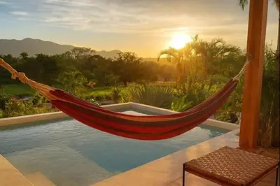 a hammock is hanging over a swimming pool at luxury wooden house mountain view in Hojancha