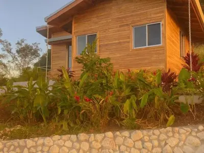 a house with a bunch of plants in front of it at luxury wooden house mountain view in Hojancha