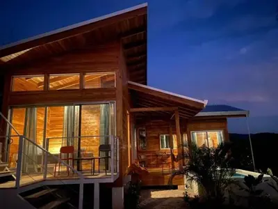 a wooden house with a balcony and a table and chairs at luxury wooden house mountain view in Hojancha