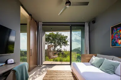 a bedroom with a bed and a large sliding glass door at Ohana Villa - Ocean View and a Walk to the Beach in Nosara
