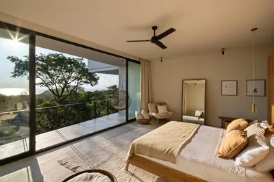 a bedroom with a bed and a balcony at Ohana Villa - Ocean View and a Walk to the Beach in Nosara