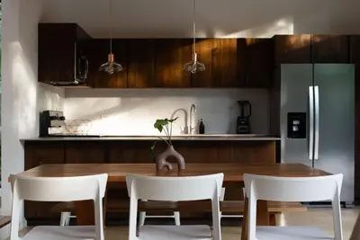 a kitchen with a wooden table and white chairs at Nalu Nosara Pool Villa Sombra in Nosara