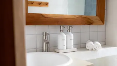 a bathroom sink with two bottles and towels on a counter at New! 5-Min Walk to Surf - Private Pool - 2BR in Playa hermosa