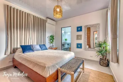 a bedroom with a large bed and a mirror at Ela Hotel Jaco in Jacó