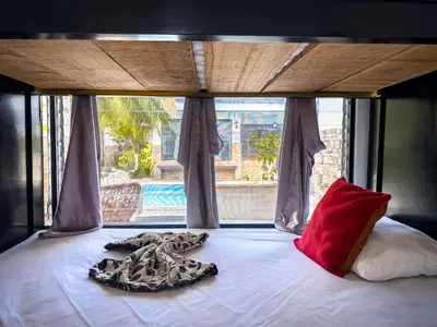 a bed with a blanket and a pillow and a window at Ela Hotel Jaco in Jacó
