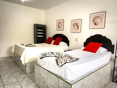 two beds in a room with red pillows at Ela Hotel Jaco in Jacó