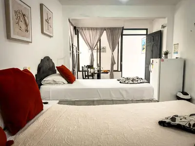 a bedroom with two beds and a refrigerator at Ela Hotel Jaco in Jacó