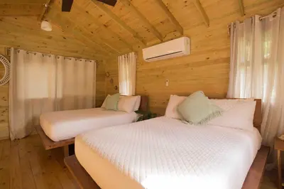 a bedroom with two beds in a wooden cabin at Finca Los Mangos in Quepos