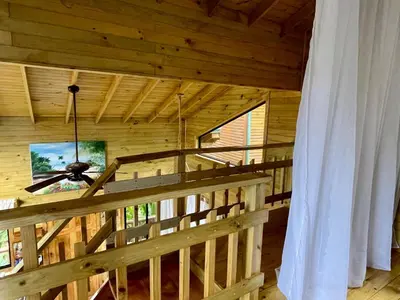 a wooden cabin with a ceiling fan and a window at Finca Los Mangos in Quepos
