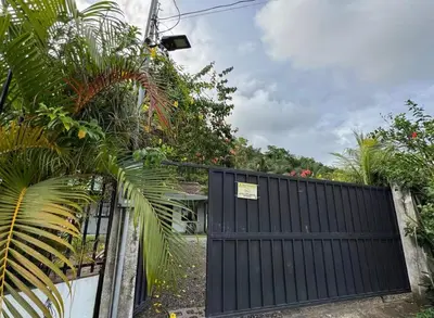 a black gate with a sign on it next to some plants at Casa Bambu in Tapantí