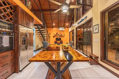 a large wooden table in a room with a refrigerator at Casa de los Lorros close to whale tail in Bahia