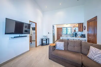 a living room with a couch and a kitchen at Casa Alegria in Jacó