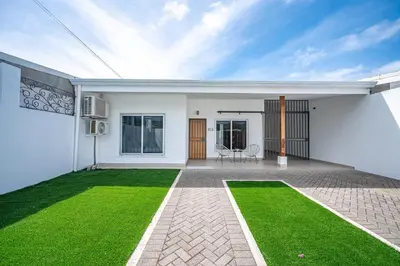 a white house with a green lawn in the backyard at Casa Alegria in Jacó